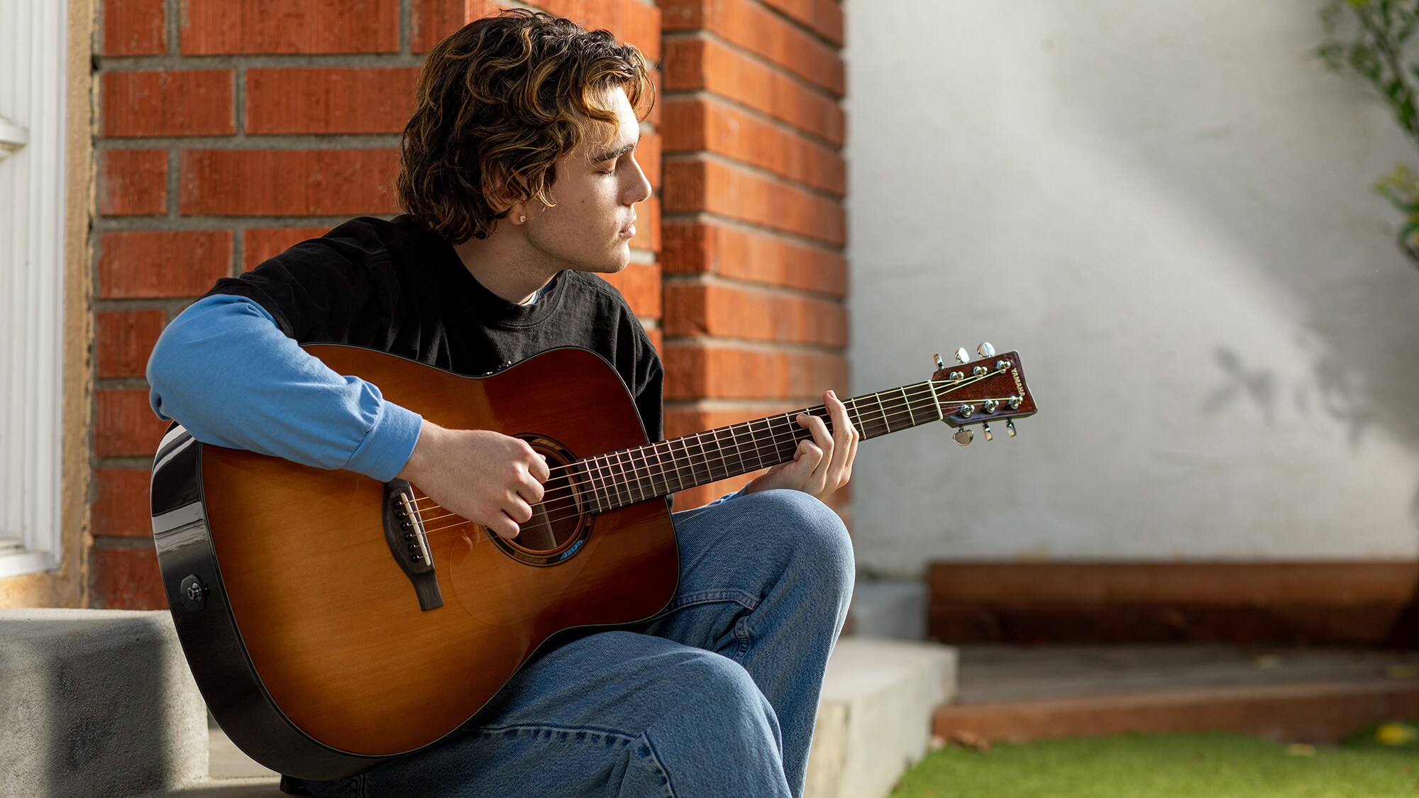 Een man bespeelt een TAG1 E akoestische gitaar buitenshuis