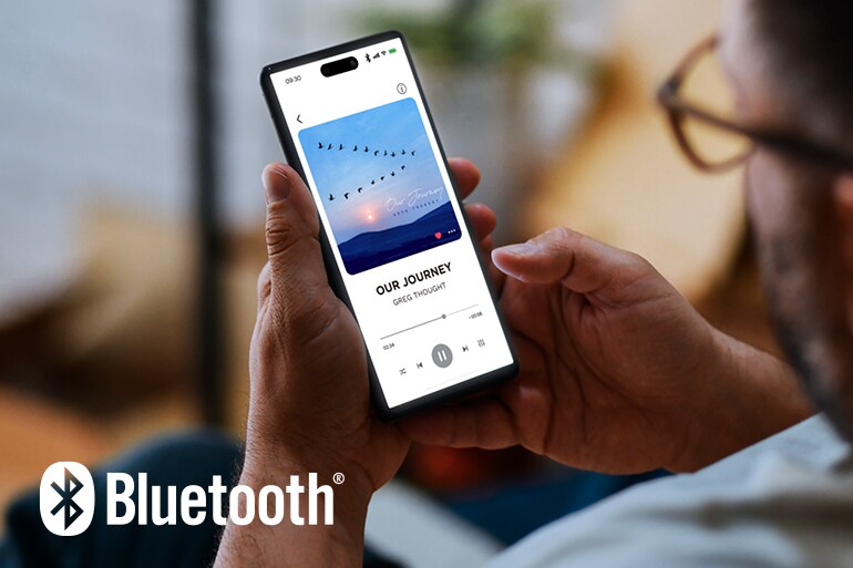 Het Bluetooth-logo en een man die een smartphone gebruikt voor het afspelen van muziek.