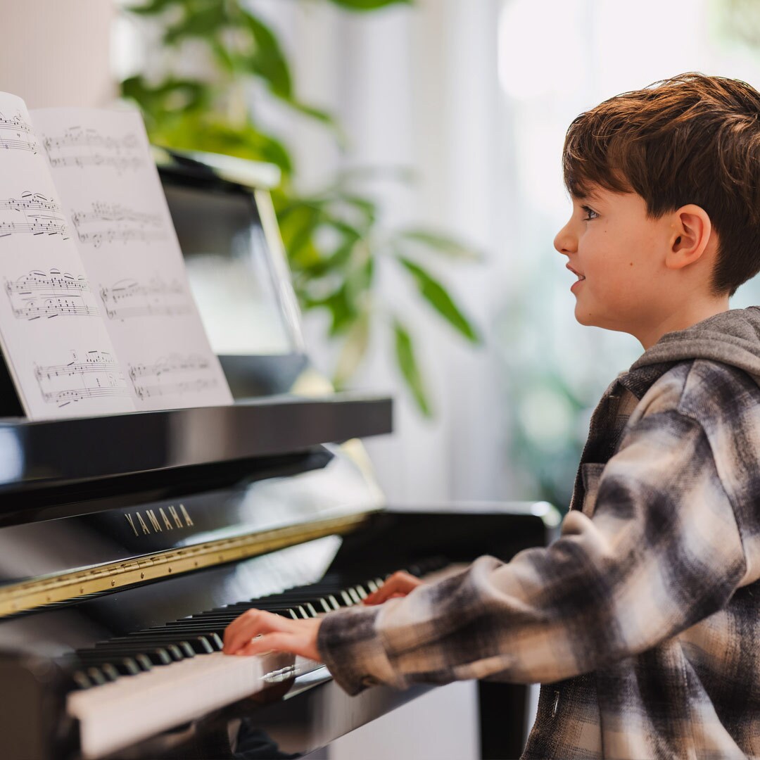 Een kind speelt met plezier op een staande piano uit de B-serie