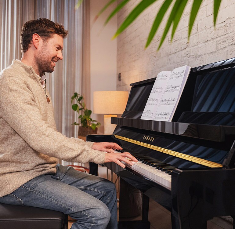 Een vrouw speelt met plezier op een staande piano uit de B-serie