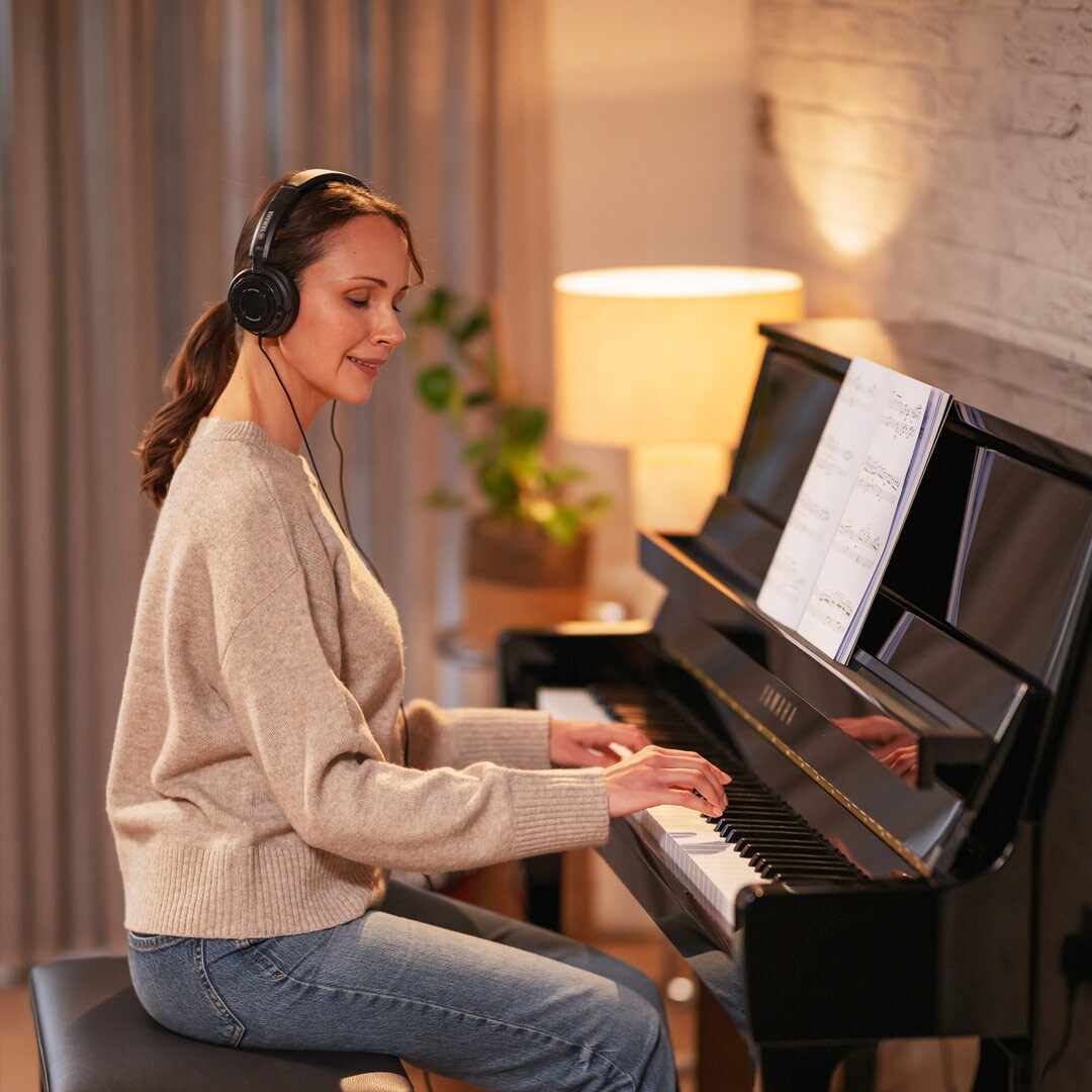 Een vrouw speelt met plezier piano terwijl ze een hoofdtelefoon draagt