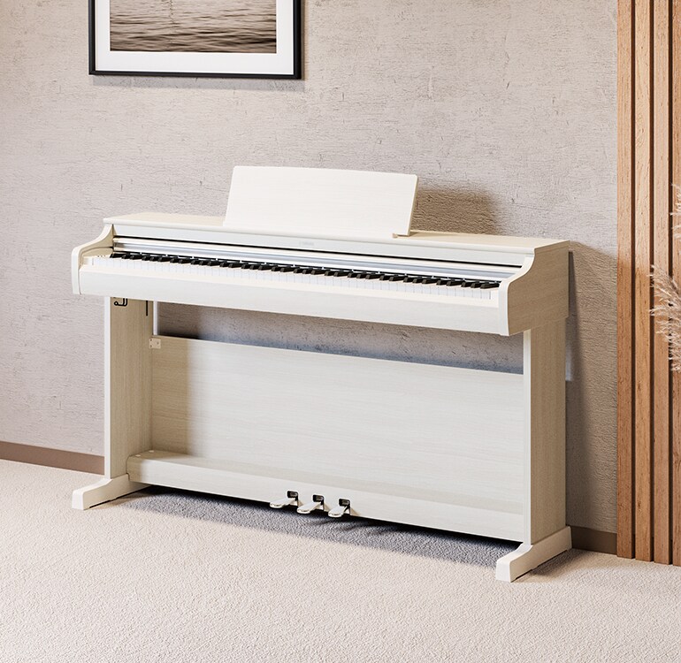 Een woonkamer met een wit berken ARIUS-piano, kamerplanten en een bank, harmonieus geïntegreerd in het interieur