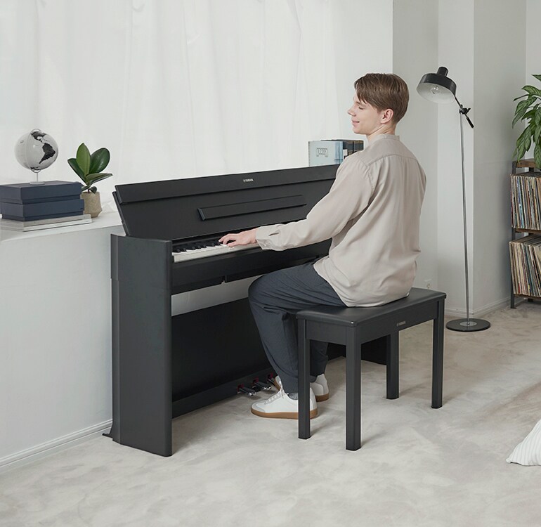 Een man die in een ontspannen setting een ARIUS-piano bespeelt in een slaapkamer