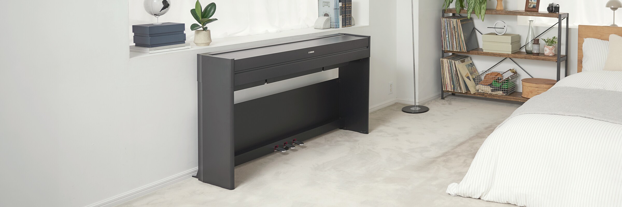 Een ARIUS-piano in een slaapkamer met gesloten klep, harmonieus geïntegreerd in het interieur